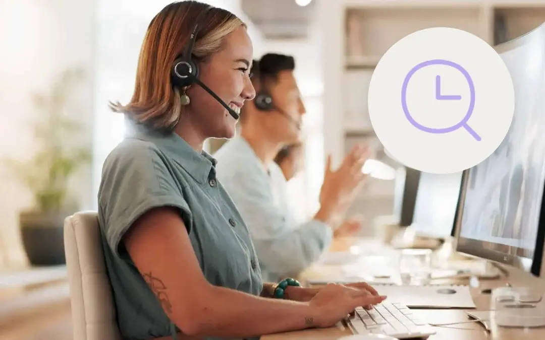 Smiling customer service agent with a headset typing at a computer beside a colleague, with a purple clock and magnifying glass icon, for a post on how often to review AI QA scores.