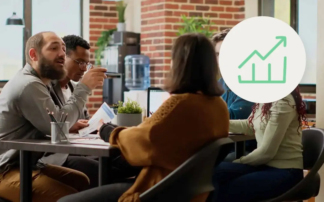 Contact center team reviewing printed reports and a laptop together at a shared desk, with a green upward trend chart icon