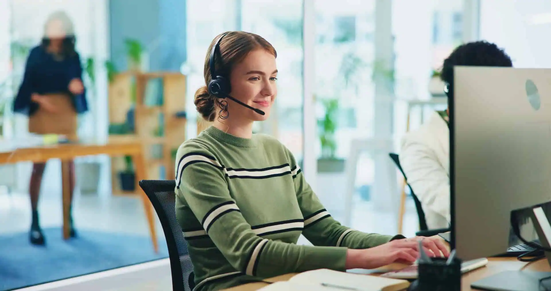 Contact center agent with a headset sitting at their desk