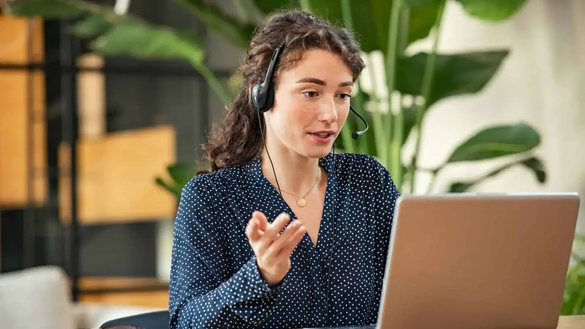Agent with laptop and plants speaking on headset at laptop