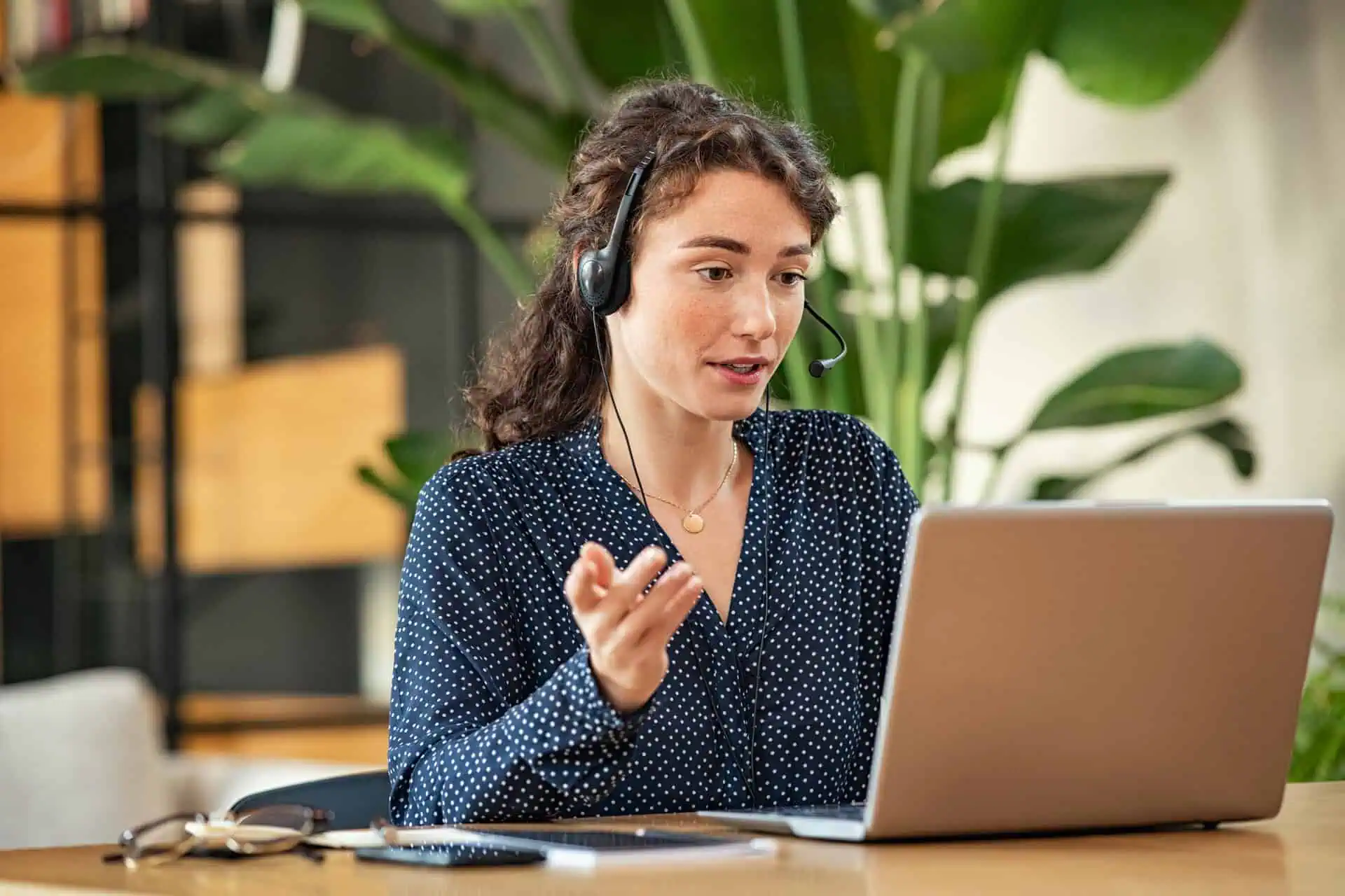 Contact center agent working on a laptop surrounded by plants