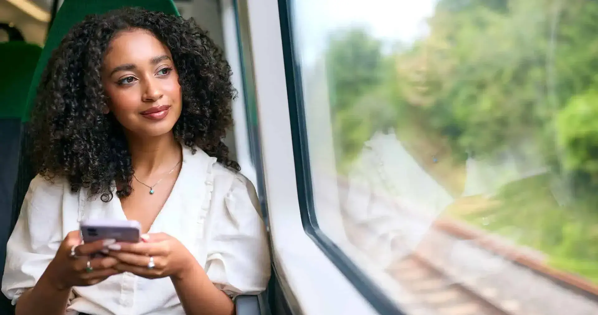 A professional using their phone on a train looking out the window