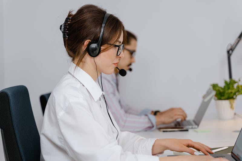 Zwei Callcenter-Agenten arbeiten mit Headsets an ihren Schreibtischen